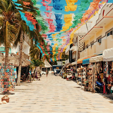 Calle del mercado de Sayulita adornada con banderines de papel picado de colores, tiendas y palmeras