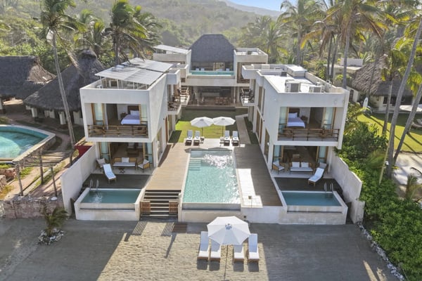 Casa amarilla de estilo colonial con piscina y palmeras en el patio