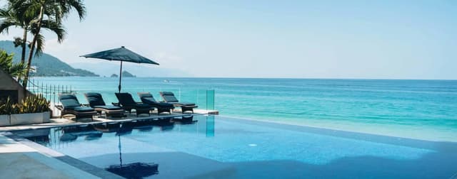 Piscina infinita con tumbonas y vistas al Pacífico
